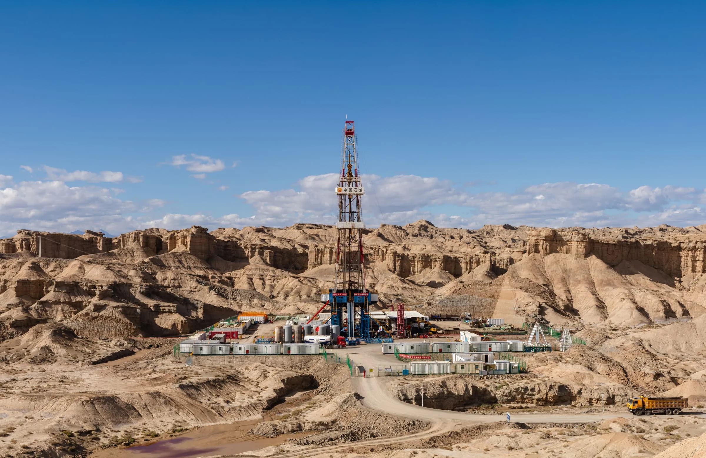 A land drilling rig on a pad in dry, broken country